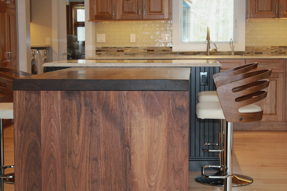 Example of a large transitional u-shaped light wood floor and beige floor open concept kitchen design in Boston with an undermount sink, raised-panel cabinets, medium tone wood cabinets, quartz countertops, multicolored backsplash, glass tile backsplash, stainless steel appliances, an island and beige countertops
