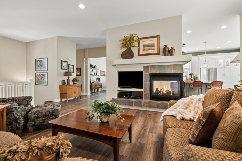 This is an example of a large traditional open plan living room in Other with brown walls, medium hardwood flooring, a two-sided fireplace, a tiled fireplace surround and brown floors.