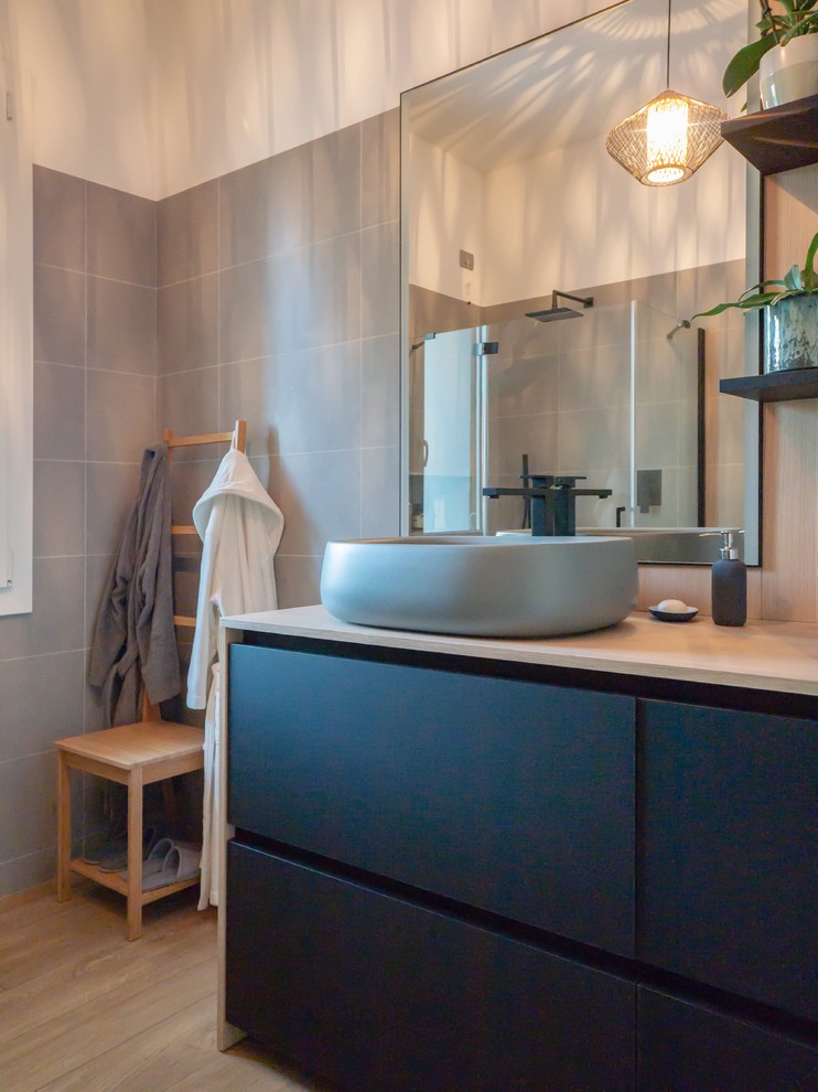 Mid-sized scandinavian 3/4 bathroom in Milan with flat-panel cabinets, black cabinets, a corner shower, a wall-mount toilet, gray tile, porcelain tile, white walls, porcelain floors, a vessel sink, wood benchtops, beige floor and a hinged shower door.