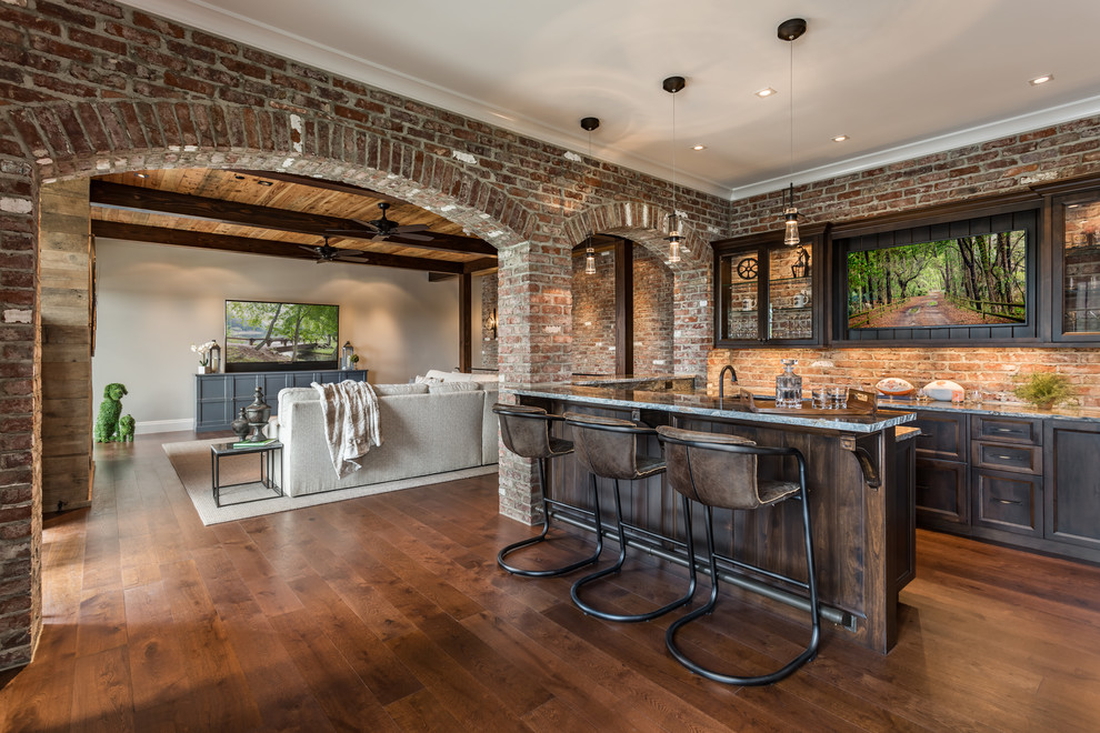 This is an example of a transitional u-shaped seated home bar in Other with dark wood cabinets, quartzite benchtops, brick splashback, recessed-panel cabinets, red splashback, dark hardwood floors, brown floor and grey benchtop.