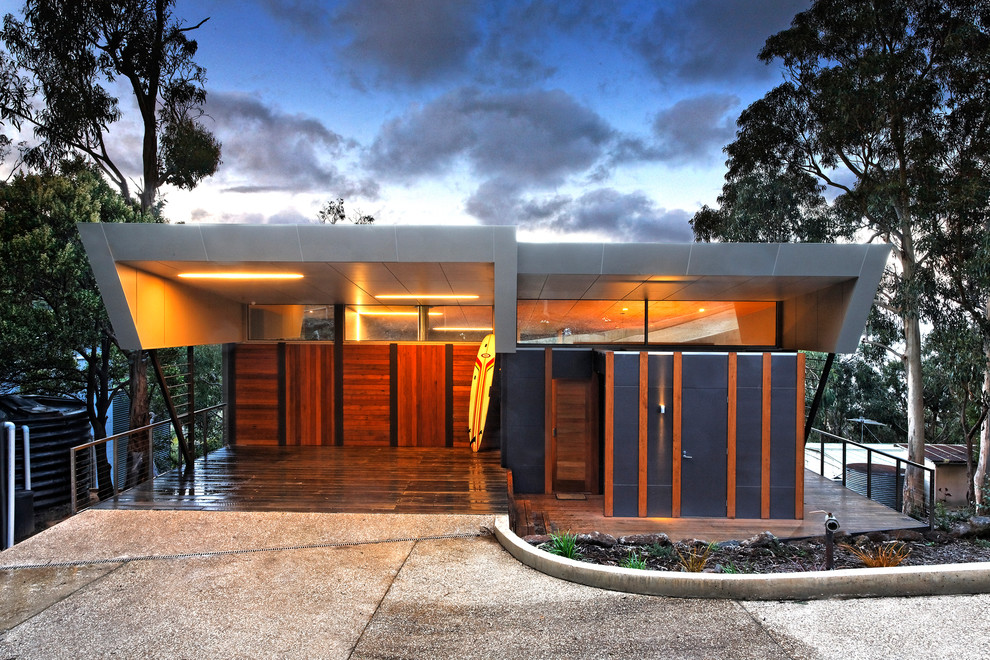 This is an example of a small beach style two-storey exterior in Melbourne with a flat roof and wood siding.