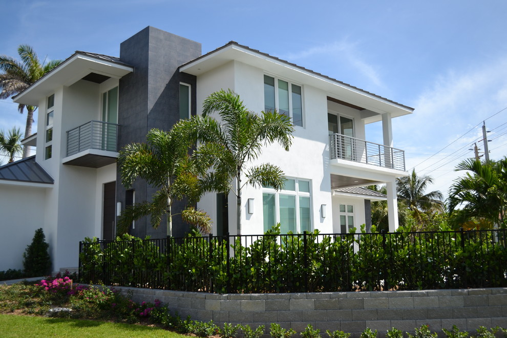 This is an example of a large contemporary two-storey adobe white house exterior in Miami with a gambrel roof and a metal roof.