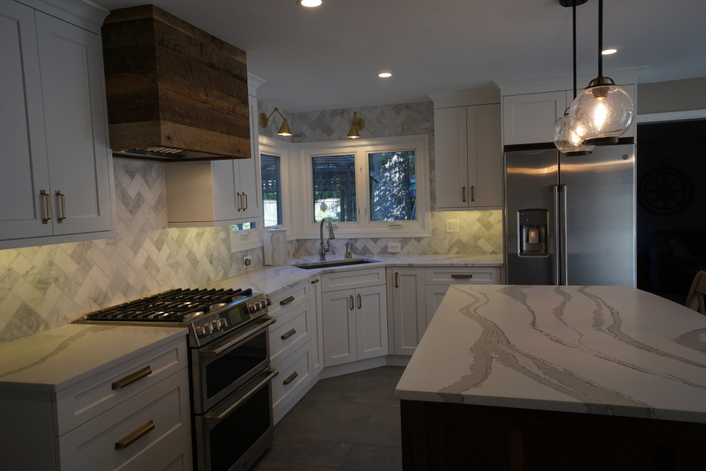 Small country l-shaped eat-in kitchen in DC Metro with an undermount sink, recessed-panel cabinets, white cabinets, quartz benchtops, white splashback, marble splashback, stainless steel appliances, porcelain floors, with island, grey floor and white benchtop.