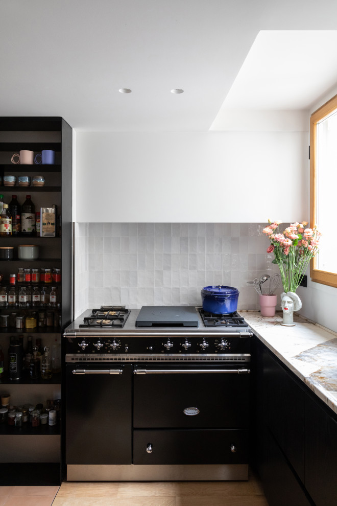 Idées déco pour cuisine ouverte en U et bois clair avec un évier intégré, un placard à porte plane, un plan de travail en quartz, une crédence blanche, une crédence en céramique, un électroménager noir, un sol en carrelage de céramique, îlot, un sol beige et un plan de travail beige.