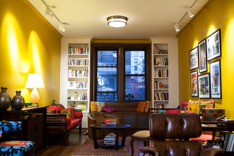 Design ideas for a mid-sized eclectic enclosed living room in New York with a library, yellow walls and dark hardwood floors.