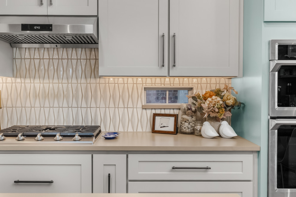 Kitchen - mid-sized transitional ceramic tile kitchen idea in Austin with an undermount sink, shaker cabinets, quartz countertops, ceramic backsplash, stainless steel appliances and an island