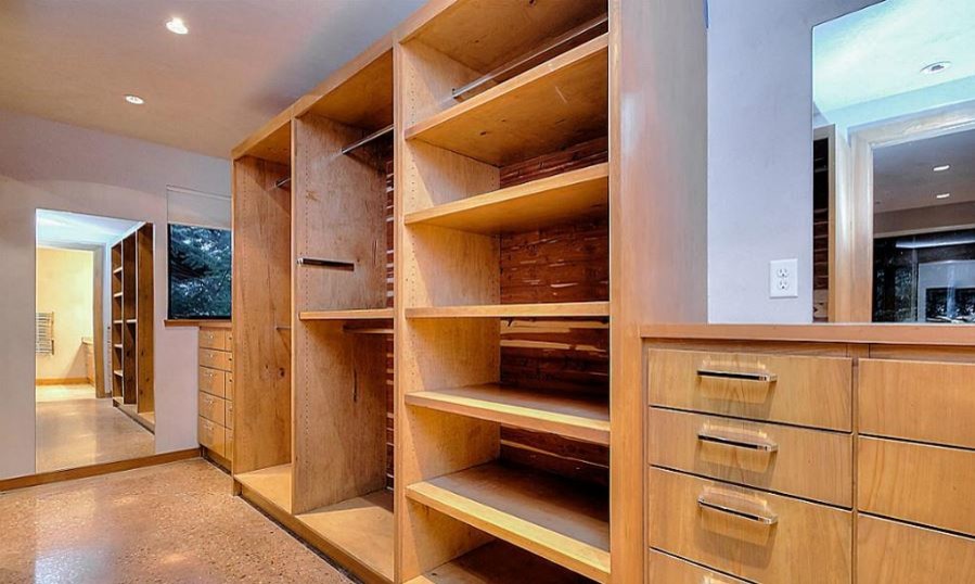 Large modern gender-neutral dressing room in Houston with flat-panel cabinets, light wood cabinets and concrete floors.