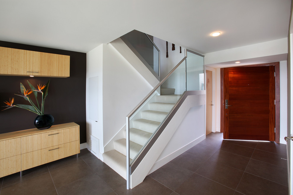 Design ideas for a small modern carpeted u-shaped staircase in Orange County with carpet risers and glass railing.