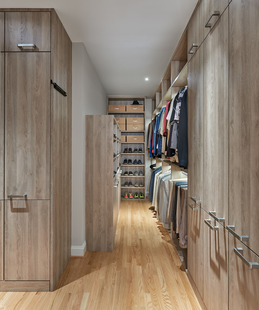 This is an example of a contemporary men's walk-in wardrobe in DC Metro with light wood cabinets and light hardwood floors.