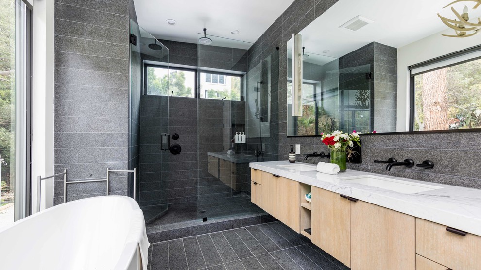 Design ideas for a contemporary master bathroom in Los Angeles with flat-panel cabinets, light wood cabinets, a freestanding tub, an alcove shower, gray tile, an undermount sink, grey floor, a hinged shower door and white benchtops.