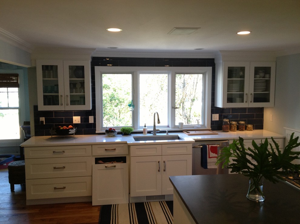 This is an example of a mid-sized transitional galley eat-in kitchen in New York with an undermount sink, shaker cabinets, white cabinets, soapstone benchtops, black splashback, porcelain splashback, stainless steel appliances and dark hardwood floors.