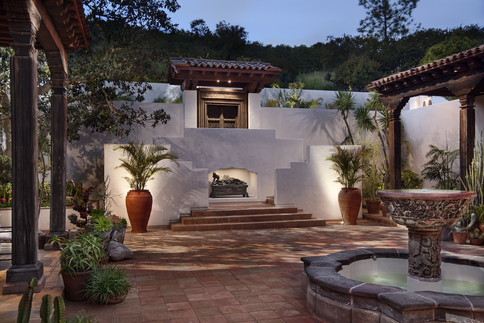 This is an example of a large asian courtyard patio in San Diego with a water feature, tile and a roof extension.