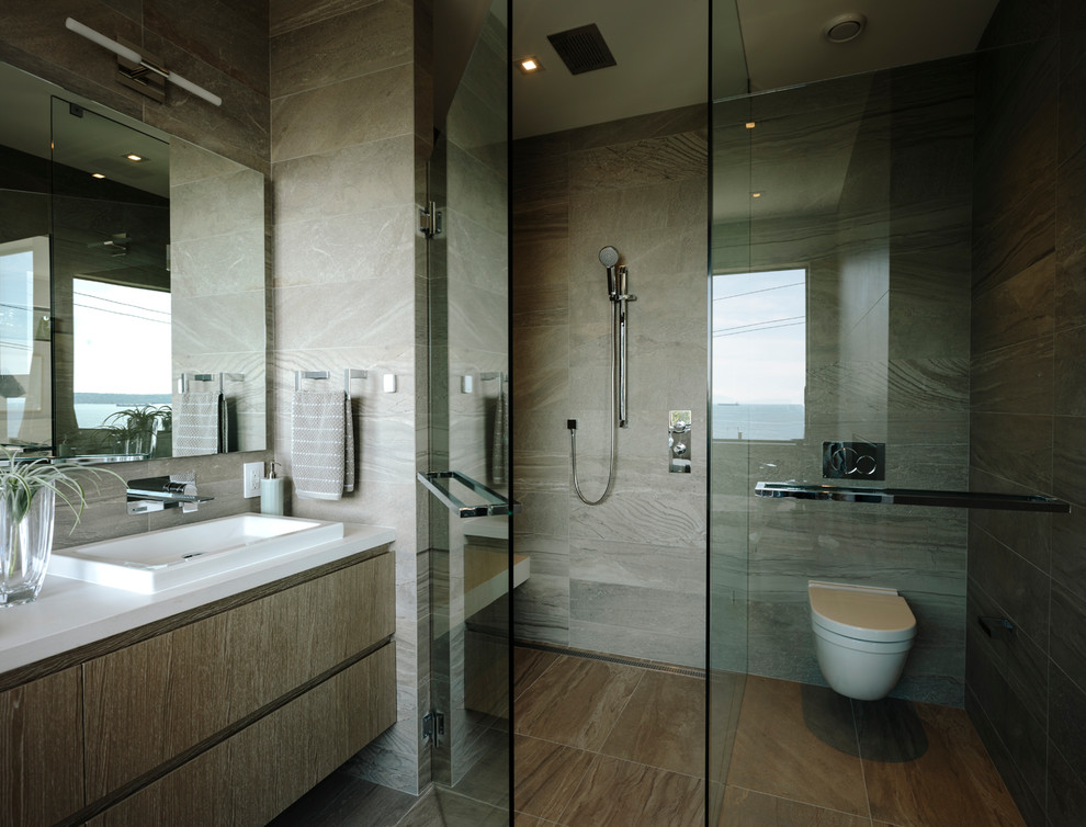 Large contemporary master bathroom in Vancouver with flat-panel cabinets, medium wood cabinets, a freestanding tub, a curbless shower, a wall-mount toilet, gray tile, porcelain tile, grey walls, porcelain floors, a vessel sink, engineered quartz benchtops, grey floor, a hinged shower door and white benchtops.