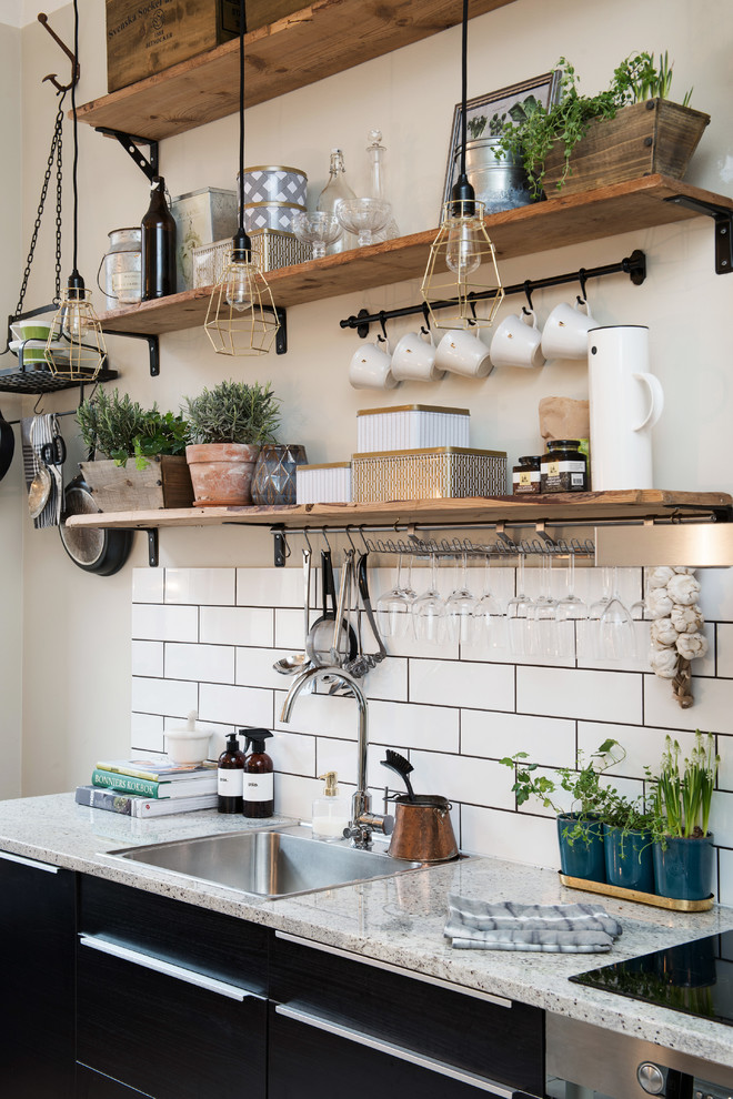 This is an example of a small country single-wall kitchen in Gothenburg with a drop-in sink, flat-panel cabinets, black cabinets, granite benchtops and no island.