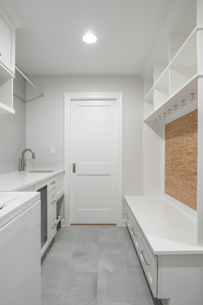 Photo of a small country single-wall utility room in Chicago with a single-bowl sink, shaker cabinets, white cabinets, quartz benchtops, grey walls, porcelain floors, a side-by-side washer and dryer, grey floor and white benchtop.