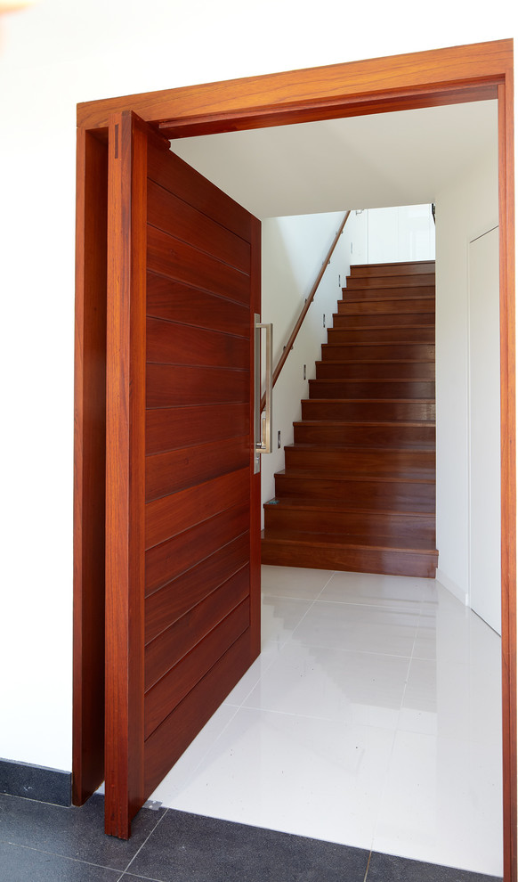 Design ideas for a small contemporary entry hall in Sydney with white walls, porcelain floors, a pivot front door and a medium wood front door.