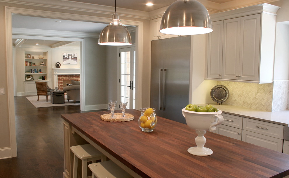 Large transitional l-shaped dark wood floor and brown floor enclosed kitchen photo in Chicago with a farmhouse sink, raised-panel cabinets, ceramic backsplash, stainless steel appliances, an island, white cabinets and gray backsplash