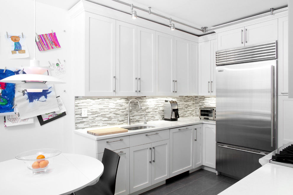 Contemporary u-shaped eat-in kitchen in New York with an undermount sink, shaker cabinets, white cabinets, grey splashback, matchstick tile splashback and stainless steel appliances.