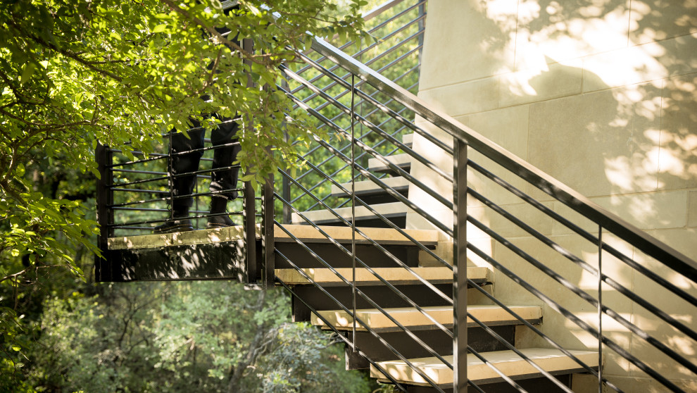 На фото: металлическая лестница на больцах, среднего размера в стиле модернизм с ступенями из известняка и металлическими перилами с