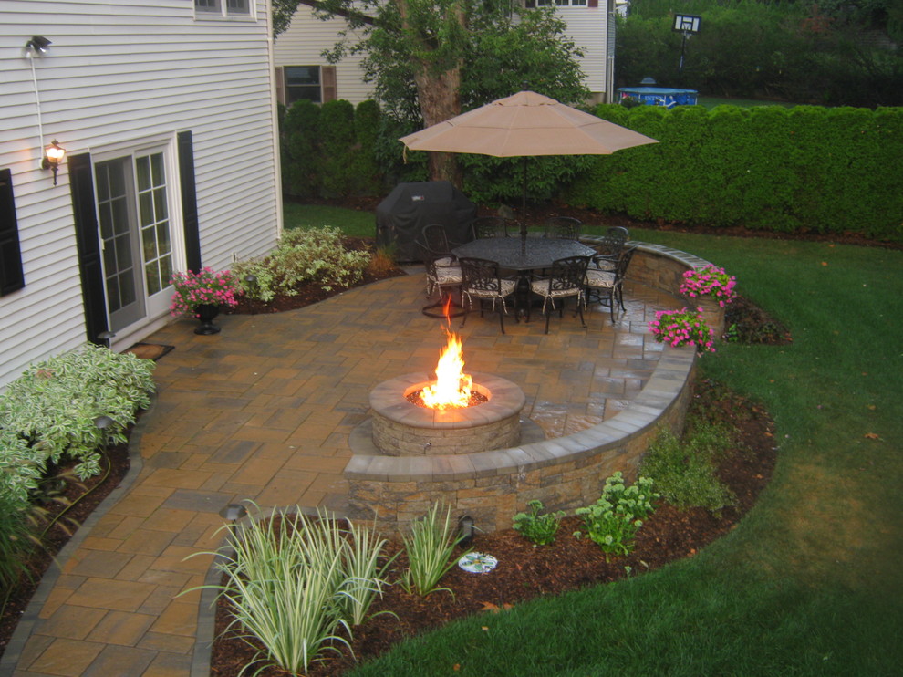 This is an example of a mid-sized traditional backyard patio in New York with no cover, a fire feature and tile.