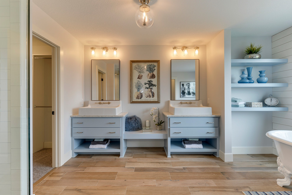 Inspiration for a mid-sized country master bathroom in Minneapolis with blue cabinets, a claw-foot tub, an open shower, a one-piece toilet, porcelain floors, a trough sink, marble benchtops, brown floor, an open shower, flat-panel cabinets and blue walls.