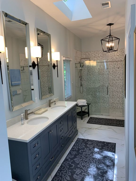 Design ideas for a mid-sized beach style master bathroom in Atlanta with shaker cabinets, white cabinets, an alcove tub, an alcove shower, a one-piece toilet, multi-coloured tile, porcelain tile, multi-coloured walls, porcelain floors, an undermount sink, engineered quartz benchtops, white floor, a hinged shower door, white benchtops, a double vanity and a freestanding vanity.