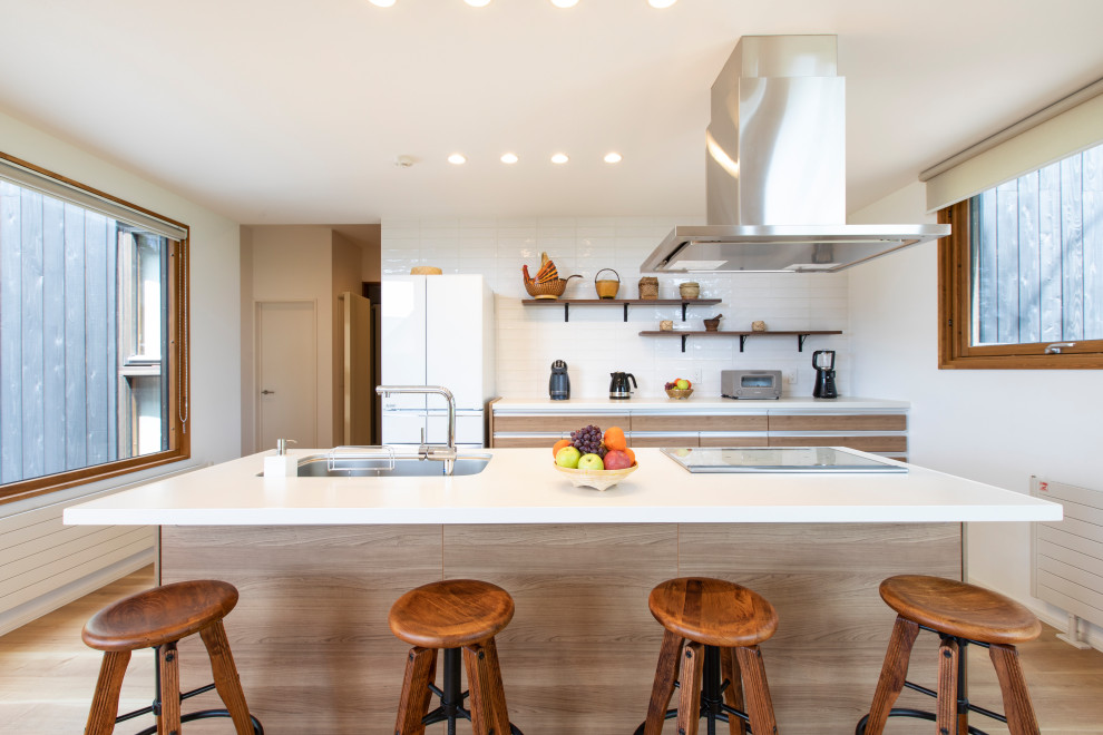Photo of a mid-sized contemporary galley kitchen in Sapporo with an undermount sink, flat-panel cabinets, light wood cabinets, white splashback, with island, beige floor and white benchtop.