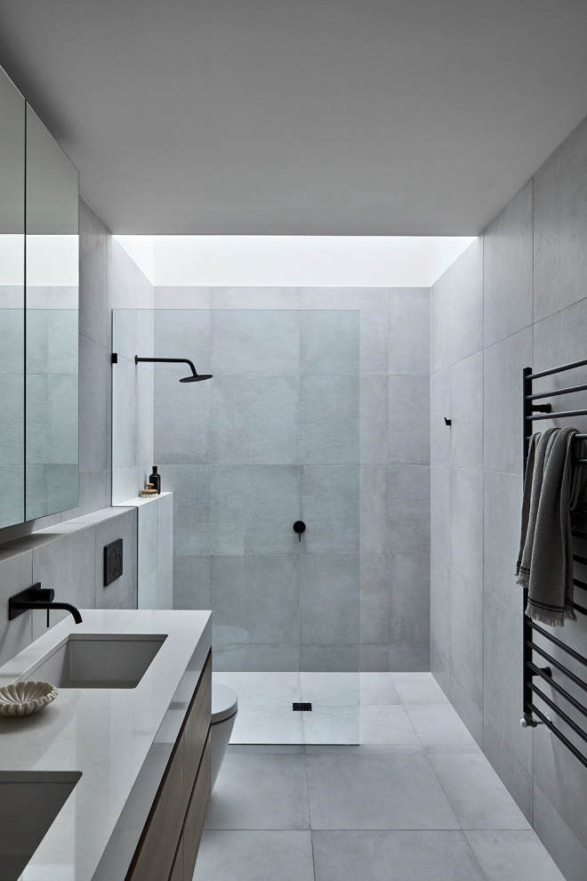 Inspiration for a small modern bathroom in Melbourne with light wood cabinets, a wall mounted toilet, grey tiles, mosaic tiles, grey walls, a submerged sink, engineered stone worktops, grey floors, grey worktops and a floating vanity unit.