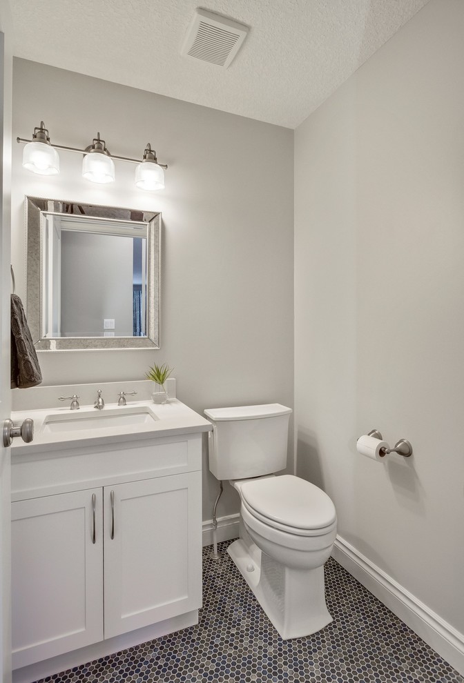 Small transitional powder room in Edmonton with shaker cabinets, white cabinets, a two-piece toilet, grey walls, porcelain floors, an undermount sink, engineered quartz benchtops, multi-coloured floor and white benchtops.