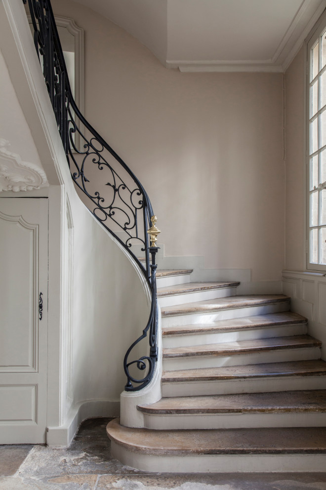 Traditional curved staircase in Paris with metal railing.