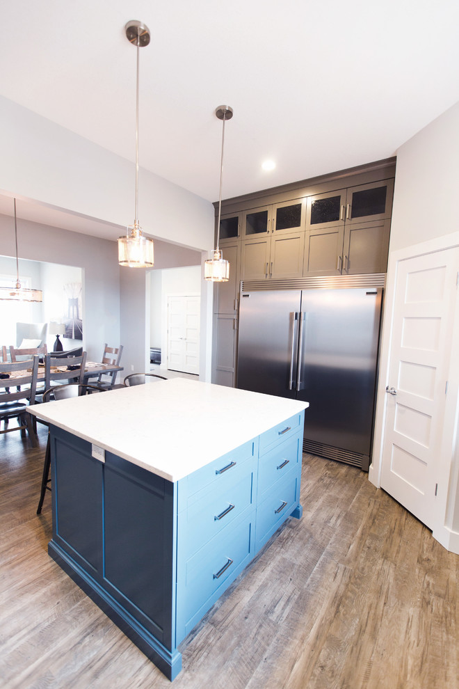 Example of a transitional laminate floor kitchen design in Calgary with gray cabinets, white backsplash, subway tile backsplash, stainless steel appliances and an island