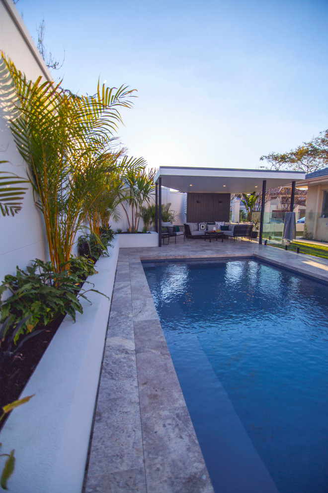 Mid-sized tropical backyard rectangular pool in Perth with with privacy feature and natural stone pavers.
