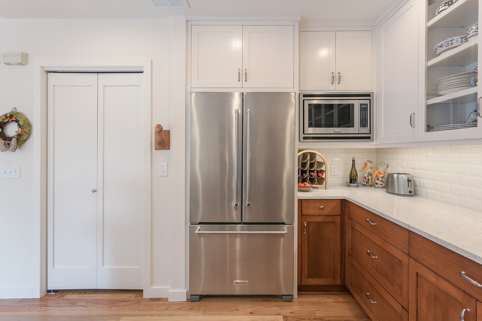 Kitchen - transitional light wood floor kitchen idea with a double-bowl sink, shaker cabinets, quartz countertops, white backsplash, subway tile backsplash and stainless steel appliances