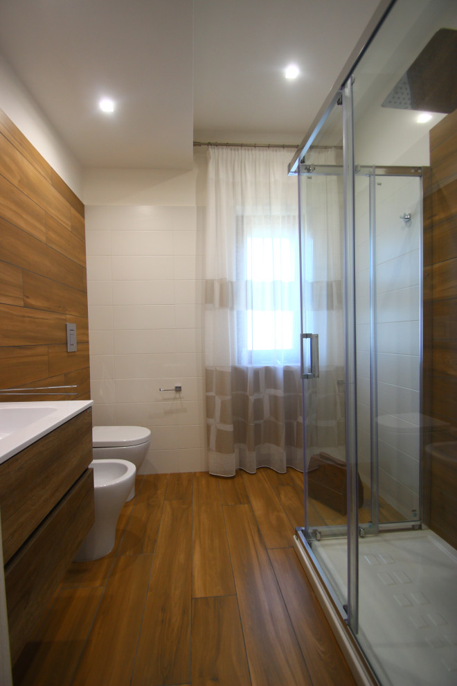 Inspiration for a small contemporary 3/4 bathroom in Naples with medium wood cabinets, a shower/bathtub combo, a two-piece toilet, white tile, porcelain tile, white walls, porcelain floors, a wall-mount sink, solid surface benchtops, brown floor, a sliding shower screen and white benchtops.