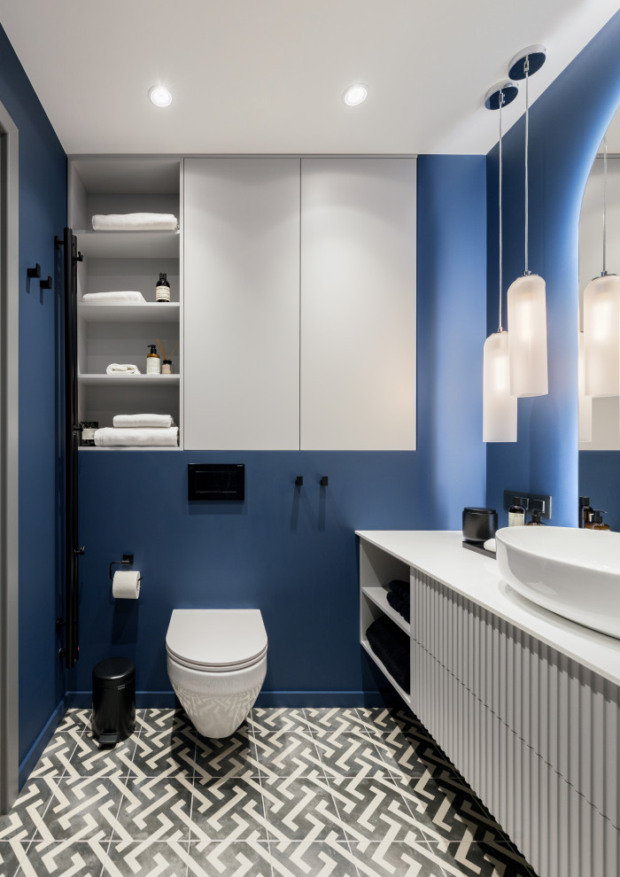 Источник вдохновения для домашнего уюта: главная ванная комната среднего размера в современном стиле с фасадами с филенкой типа жалюзи, белыми фасадами, полновстраиваемой ванной, душем над ванной, инсталляцией, синей плиткой, керамической плиткой, синими стенами, полом из керамической плитки, настольной раковиной, столешницей из искусственного камня, серым полом, шторкой для ванной, белой столешницей, тумбой под одну раковину и подвесной тумбой