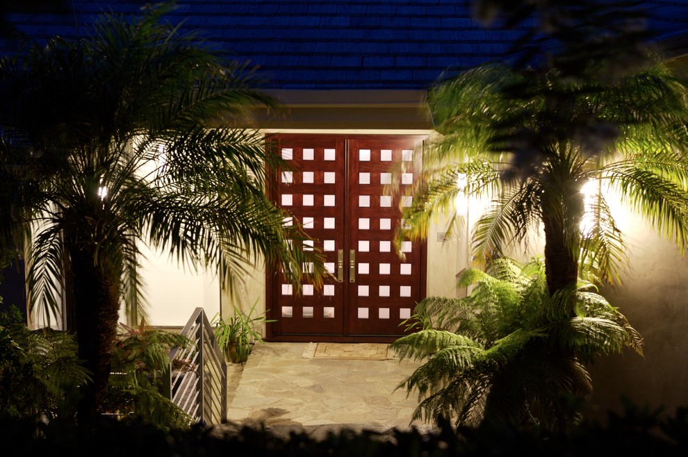 This is an example of a mid-sized tropical front door in San Diego with white walls, travertine floors, a double front door, a dark wood front door and beige floor.