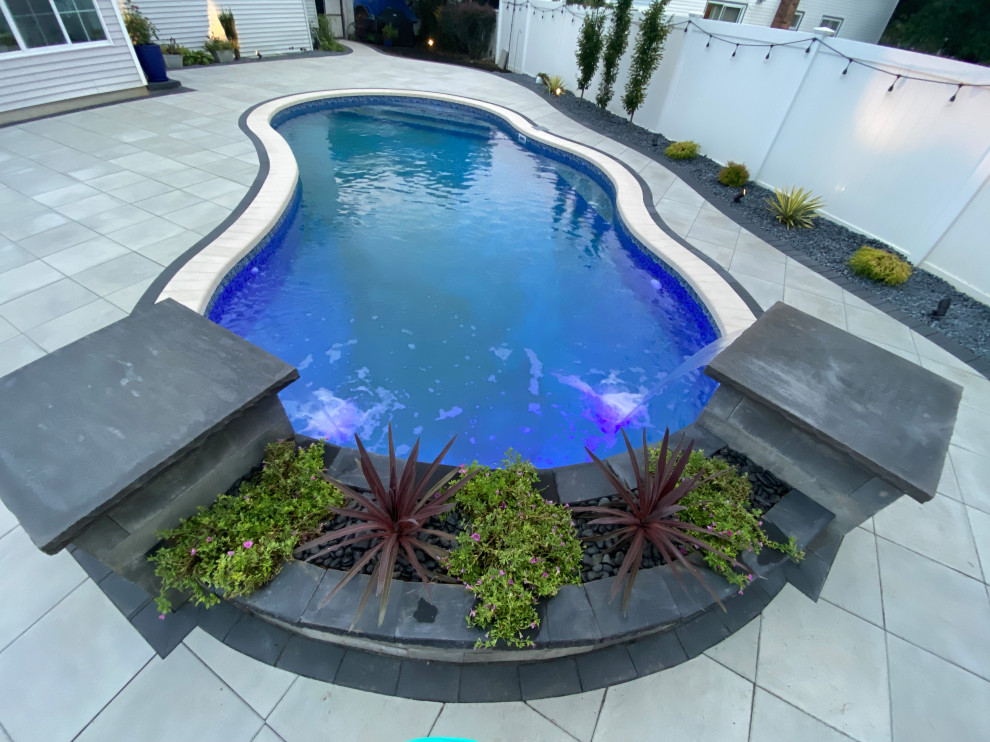 Пример оригинального дизайна: большой спортивный бассейн в форме фасоли на заднем дворе в стиле модернизм с фонтаном и мощением тротуарной плиткой