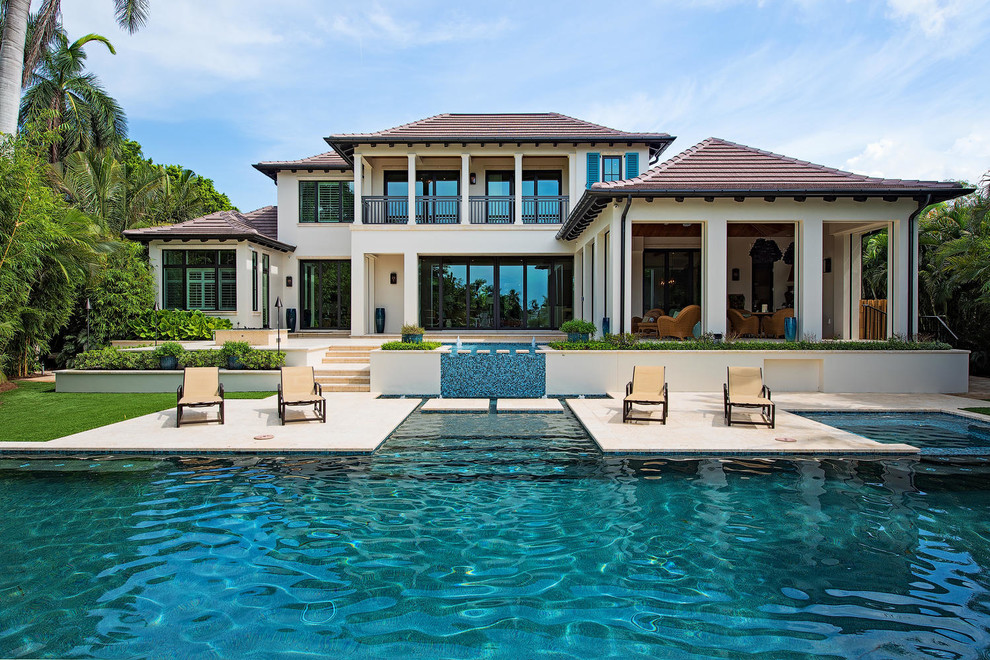 Inspiration for a large transitional backyard custom-shaped infinity pool in Miami with a hot tub and tile.