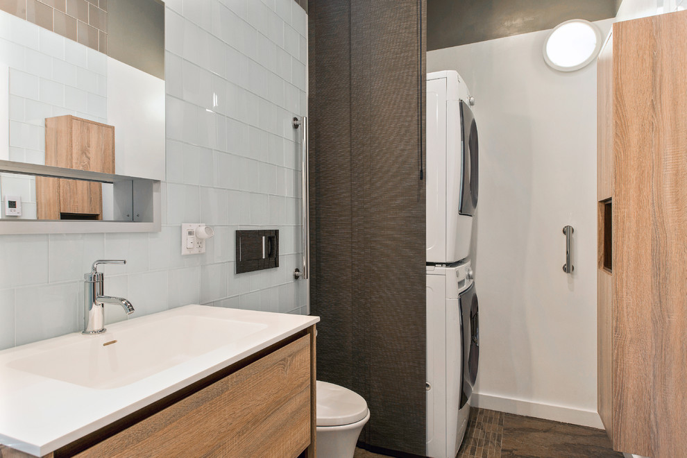 Photo of a mid-sized contemporary master bathroom in San Francisco with flat-panel cabinets, light wood cabinets, a drop-in tub, an alcove shower, white tile, glass tile, white walls, slate floors, an integrated sink, solid surface benchtops, a wall-mount toilet and a laundry.