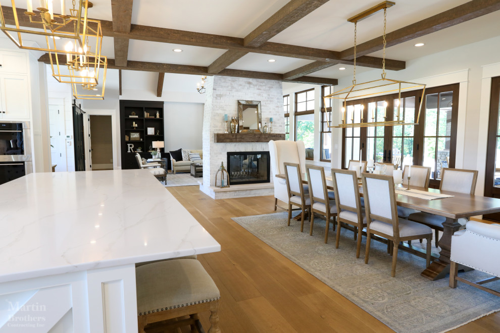 This is an example of a large country l-shaped eat-in kitchen in Other with a farmhouse sink, recessed-panel cabinets, white cabinets, quartz benchtops, white splashback, marble splashback, panelled appliances, light hardwood floors, with island, white benchtop and coffered.