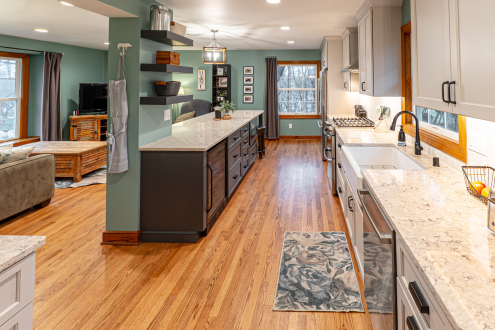 Foto på ett mellanstort lantligt flerfärgad kök, med en rustik diskho, skåp i shakerstil, beige skåp, bänkskiva i kvarts, vitt stänkskydd, stänkskydd i mosaik, rostfria vitvaror, mellanmörkt trägolv, en halv köksö och brunt golv