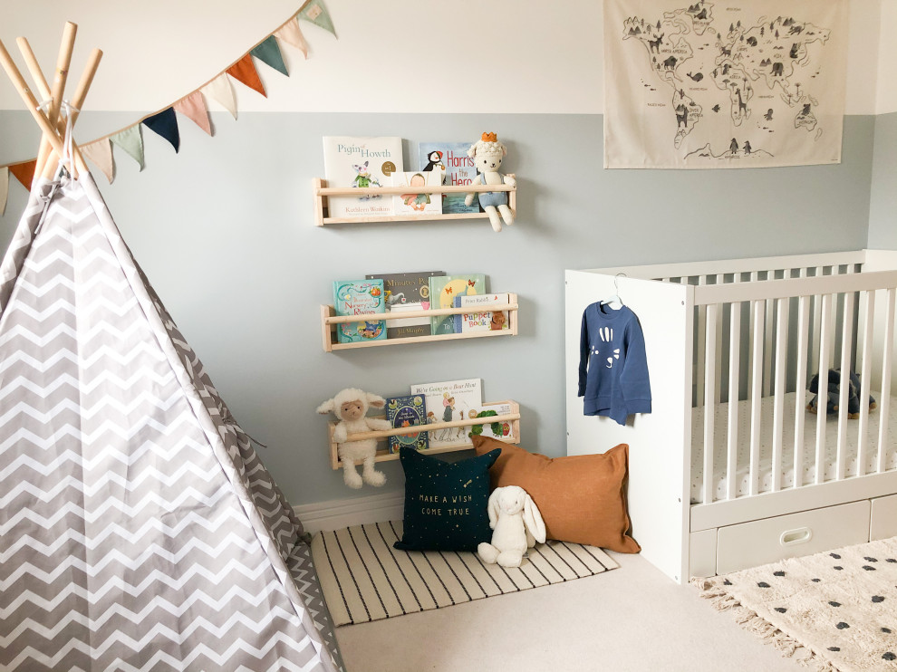 This is an example of a small modern nursery for boys in Edinburgh with blue walls, carpet and beige floors.
