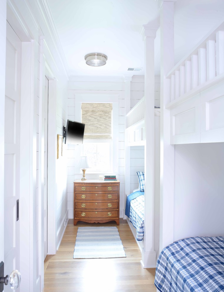Beach style gender-neutral kids' bedroom in Charleston with white walls, medium hardwood floors and brown floor.