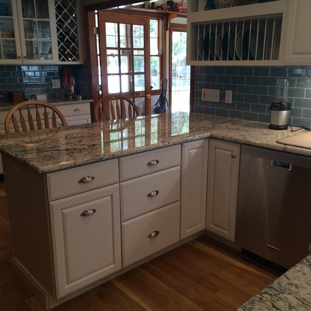 Eat-in kitchen - transitional u-shaped medium tone wood floor eat-in kitchen idea in Boston with an undermount sink, raised-panel cabinets, white cabinets, granite countertops, blue backsplash, glass tile backsplash, stainless steel appliances and an island