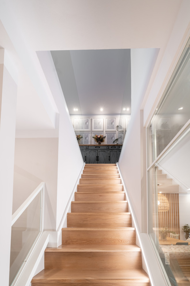 Inspiration pour un escalier droit nordique de taille moyenne avec des marches en bois, des contremarches en bois et un garde-corps en verre.