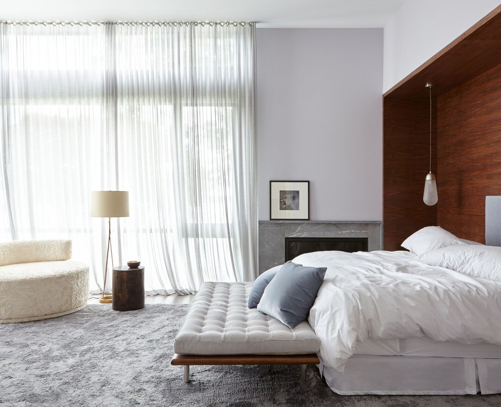 Inspiration for a contemporary bedroom in New York with grey walls and a corner fireplace.