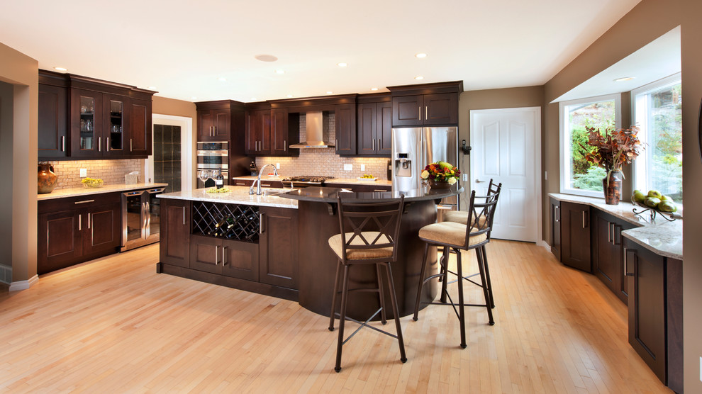 Example of a large u-shaped light wood floor eat-in kitchen design in Vancouver with an undermount sink, recessed-panel cabinets, dark wood cabinets, glass tile backsplash, stainless steel appliances and an island