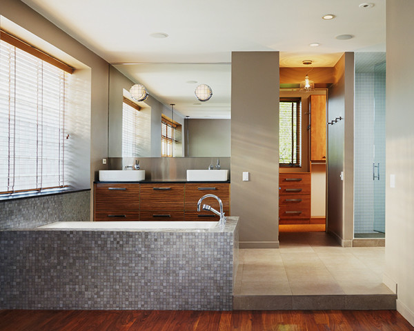 This is an example of a small industrial master bathroom in Chicago with an undermount sink, flat-panel cabinets, medium wood cabinets, limestone benchtops, an undermount tub, a corner shower, a one-piece toilet, gray tile, brown walls and porcelain floors.