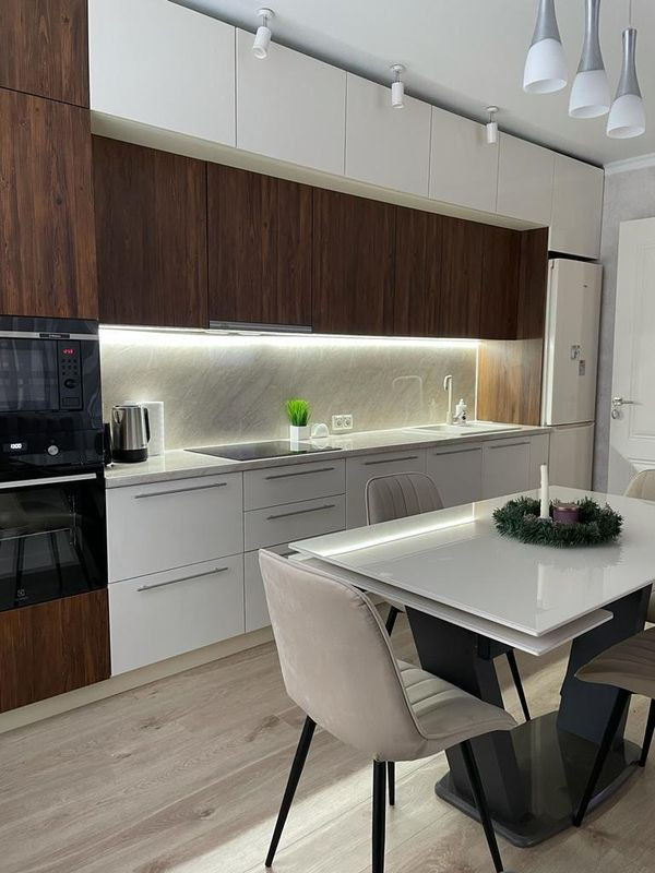 Прямая стильная кухня под потолок с глянцевыми и древесными фасадами