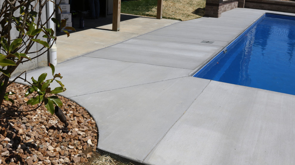 Diseño de piscina natural contemporánea grande rectangular en patio trasero con losas de hormigón